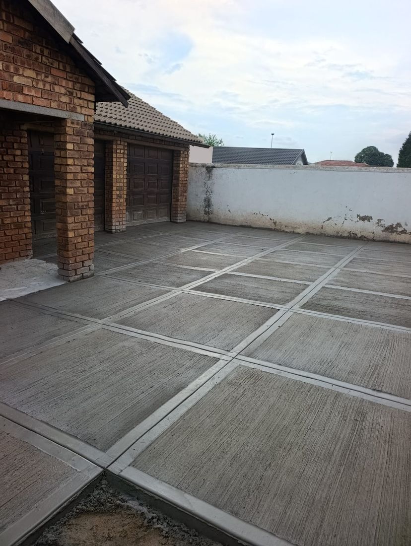 Large-format scored grey concrete patio next to a brick house