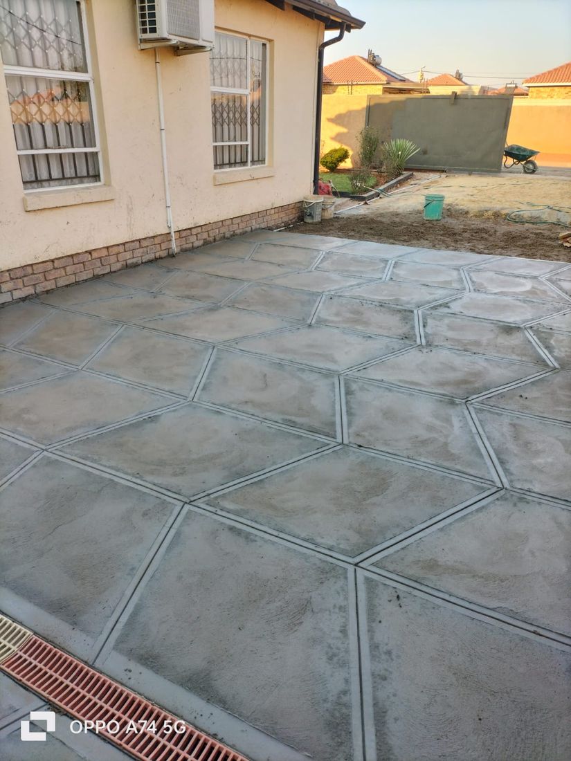 Large-format square scored concrete driveway beside a red brick home
