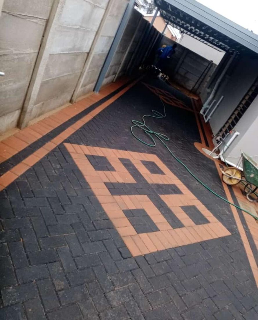 Black and orange geometric feature design inset within a dark herringbone concrete courtyard