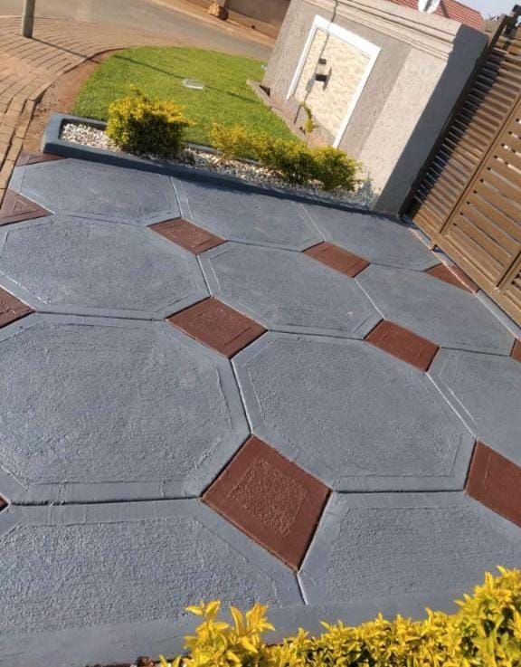 Grey octagon pattern decorative concrete driveway with terracotta diamond accents beside a garden