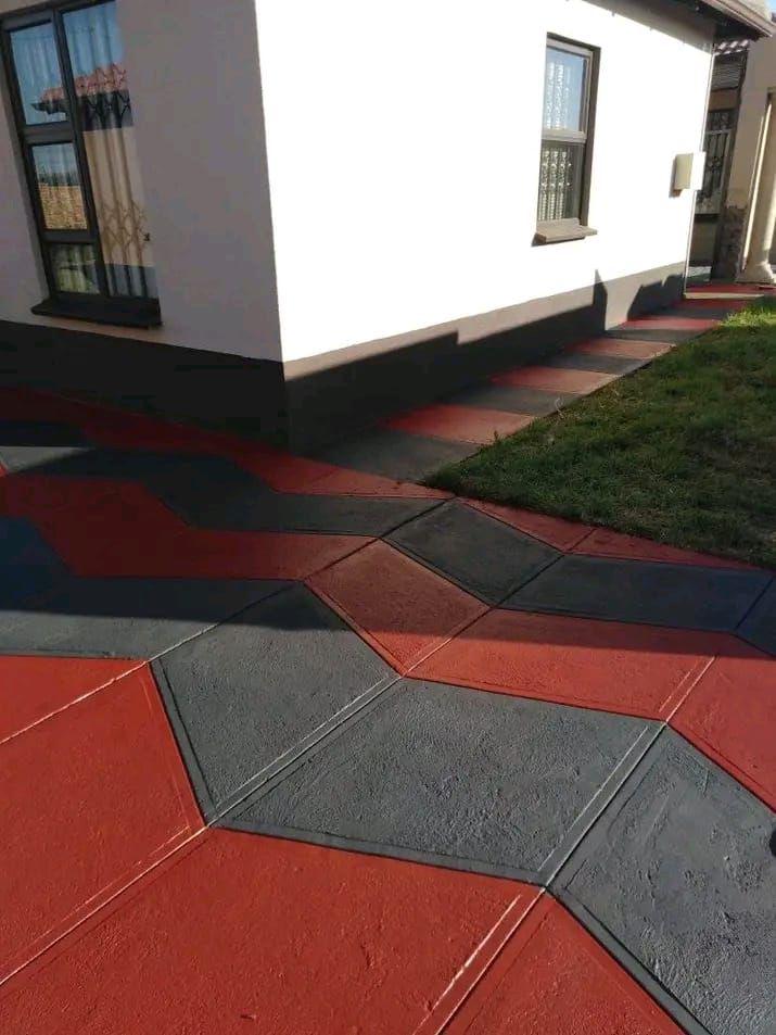 Red and charcoal diagonal chevron pattern concrete entrance path beside a garden