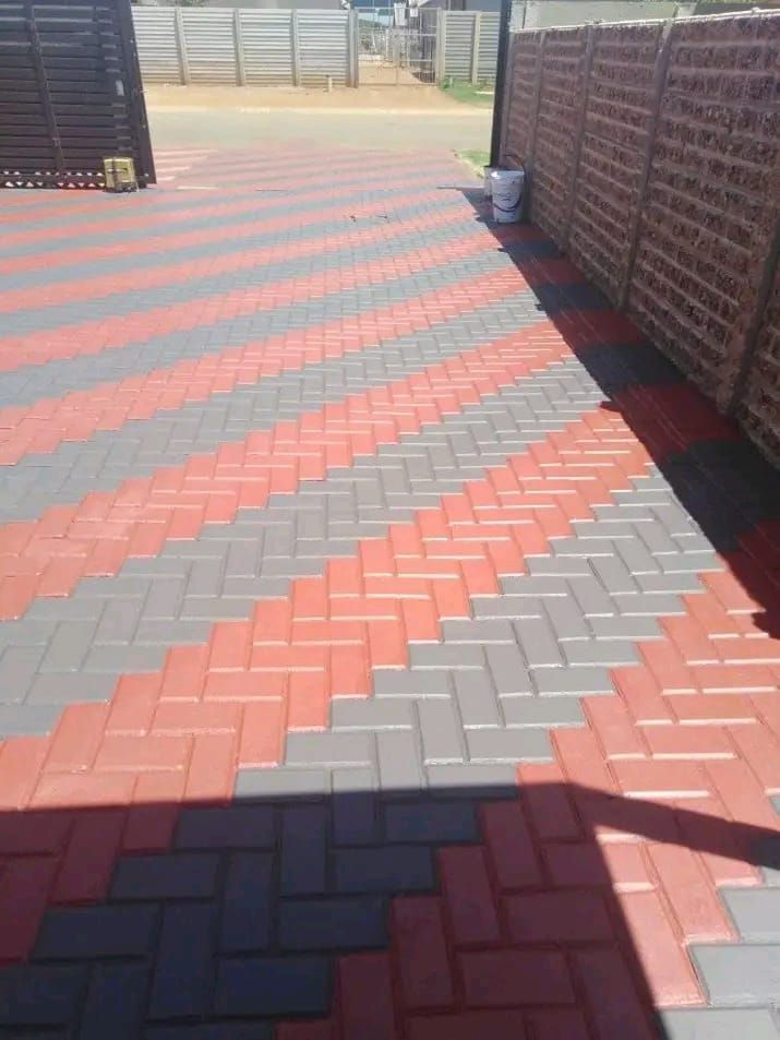 Red and salmon striped chevron pattern concrete path along a boundary wall