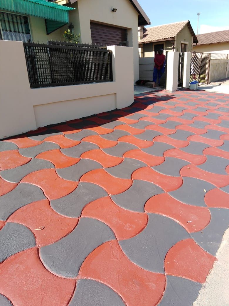 Red and grey wave pattern decorative concrete courtyard beside a black fence