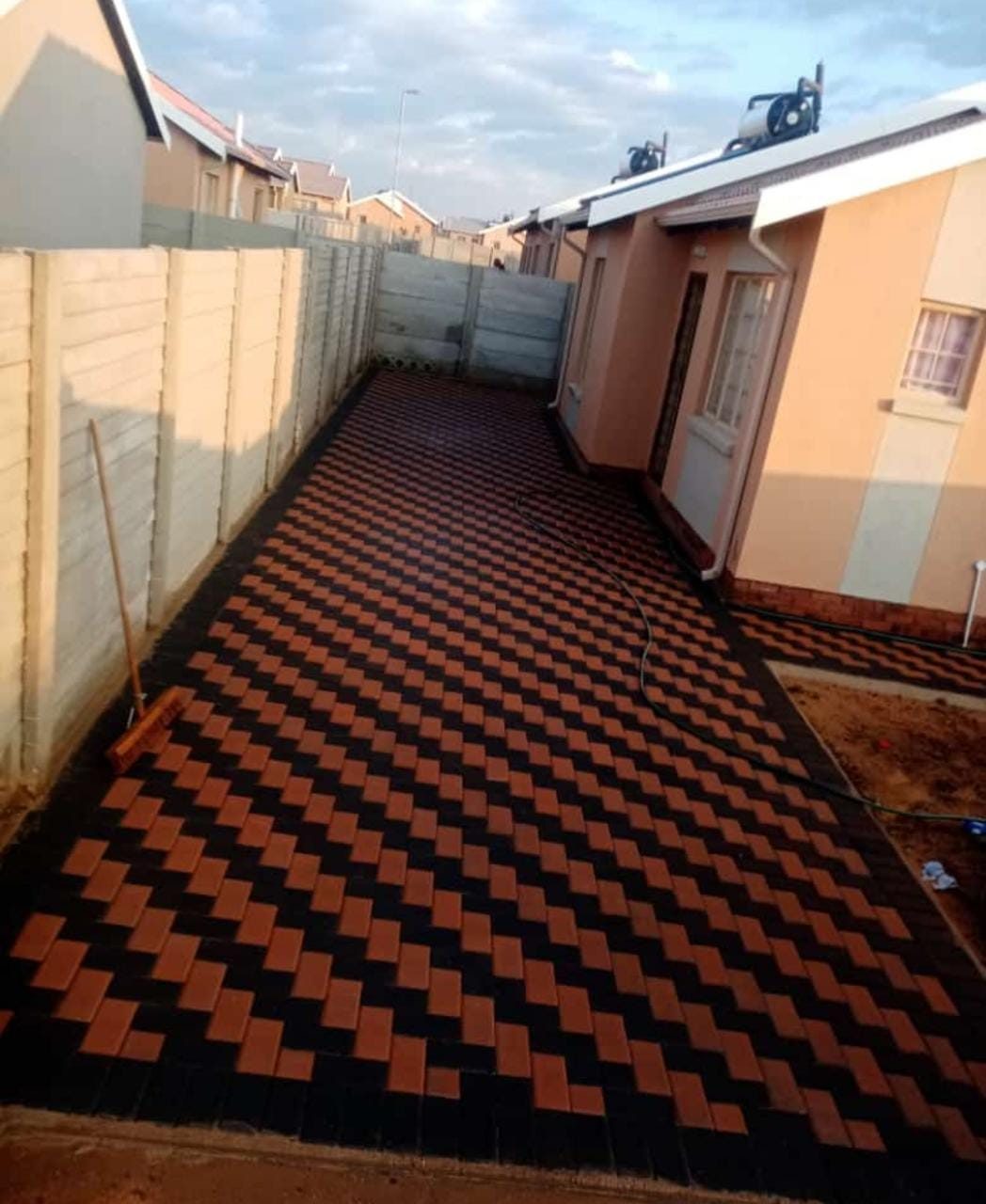 Elegant black and red herringbone-pattern decorative concrete walkway between two houses
