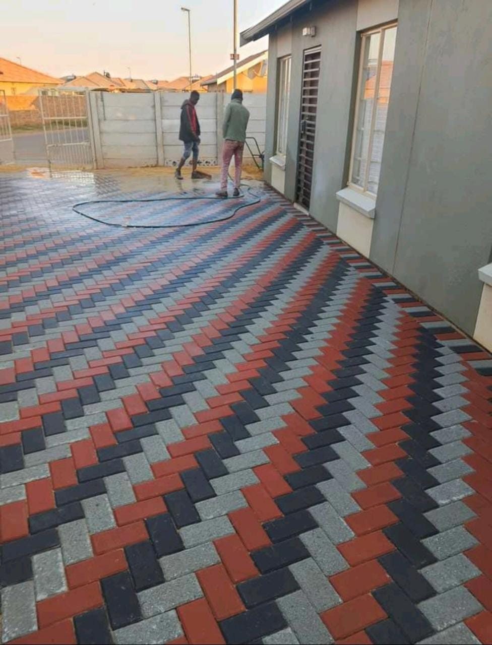Jimmalo Styles Construction team finishing a freshly laid red, black and grey herringbone brick driveway